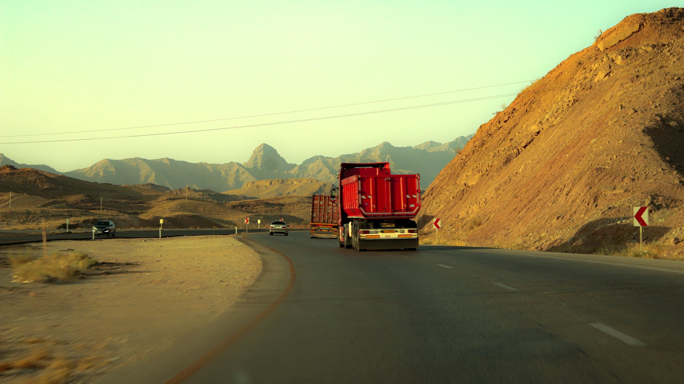 A truck climbing a desert highway between sandstone hills